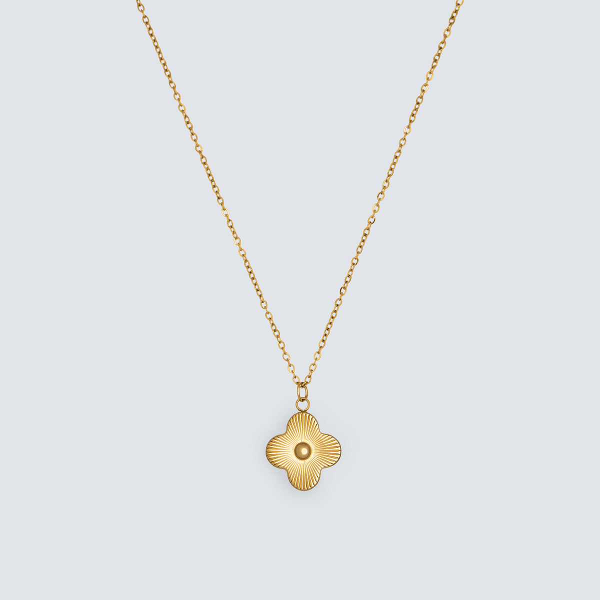Amarelle Luce clover pendant necklace in flat lay with polished reflective surface